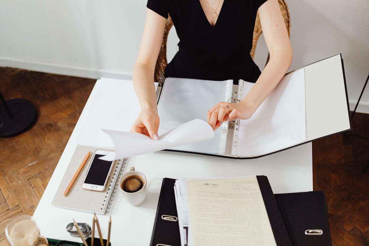 Business professional working with documents at a desk with coffee and smartphone.